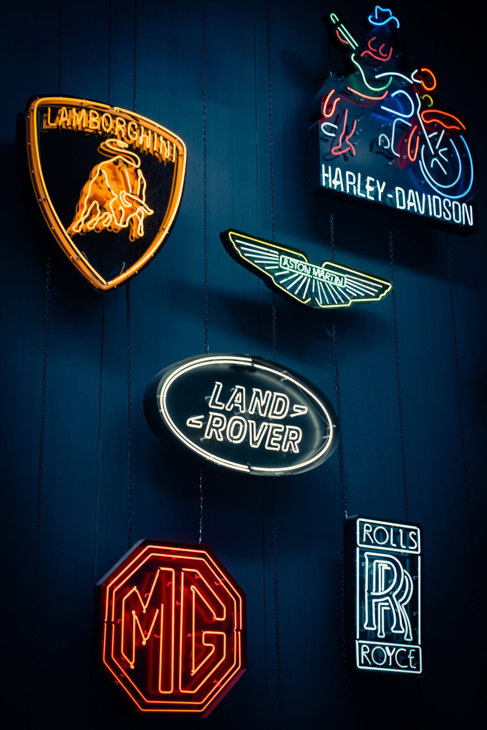 Glowing neon signs of iconic brand logos illustrating common mistakes in logo designing on a dark wall.